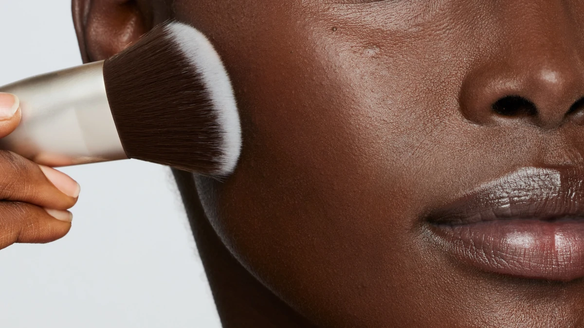 A close up image of a woman's cheek and lips who applies makeup using a foundation brush. Used to showcase Fox Collective's lifestyle and beauty PR expertise.